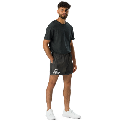 Person wearing black athletic shorts with white “BIG HEAL ENERGY” text on lower right leg. Premium textured fabric with subtle worn tones.
