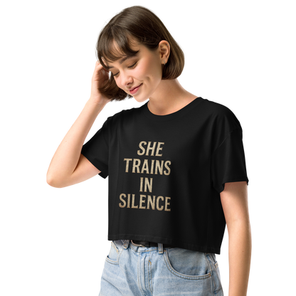Model wearing black cropped tee with gold serif text “She Trains in Silence” – women’s relaxed fit workout crop from The Lost Soul Co.